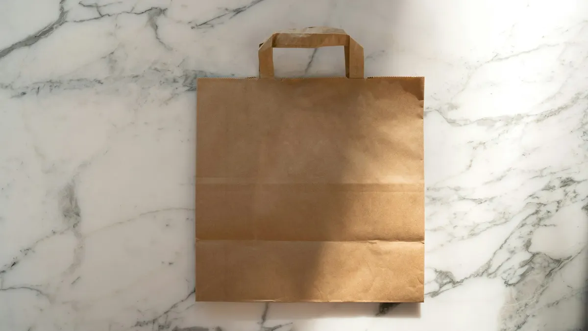 大理石の上に置かれたクラフト紙の買い物袋。今月の買い物を振り返るイメージ。