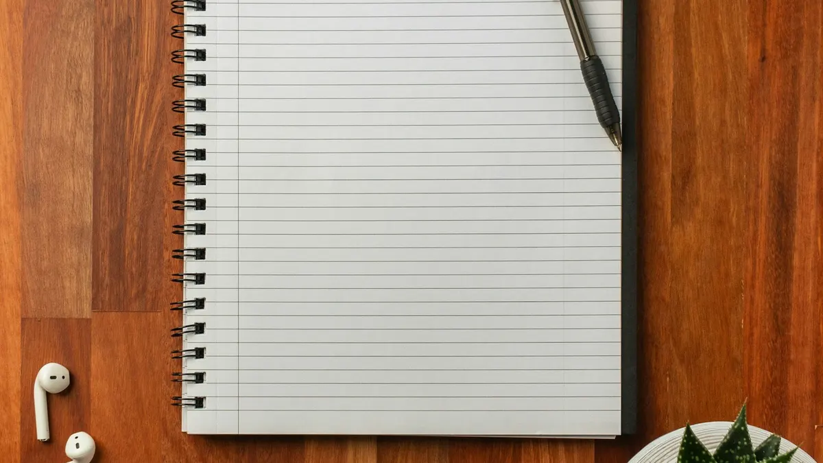 開いたノートとペン。収支を書き出すイメージ。