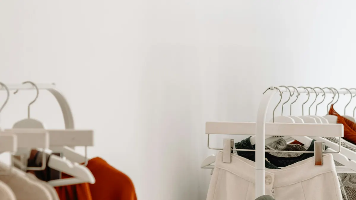 明るい店内に並ぶ落ち着いた色合いの洋服ラックと観葉植物。見切りの判断のイメージ。