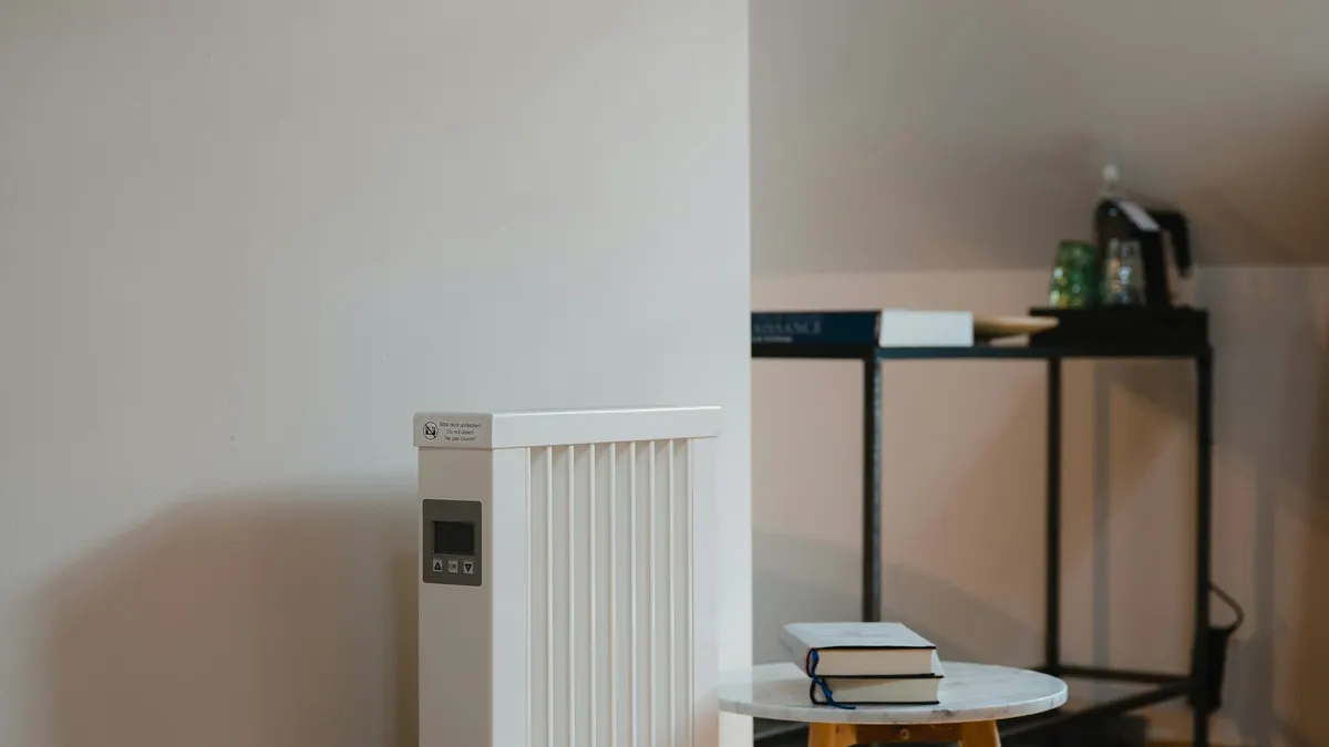 明るいリビングの壁際に置かれた白いオイルヒーター。秋の暖房家電のイメージ。