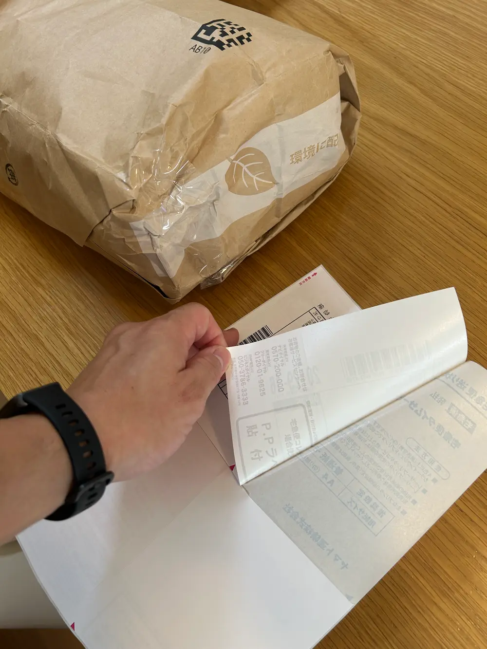 印刷した送り状のラベル部分を剥がして、梱包した荷物に貼っているところ。