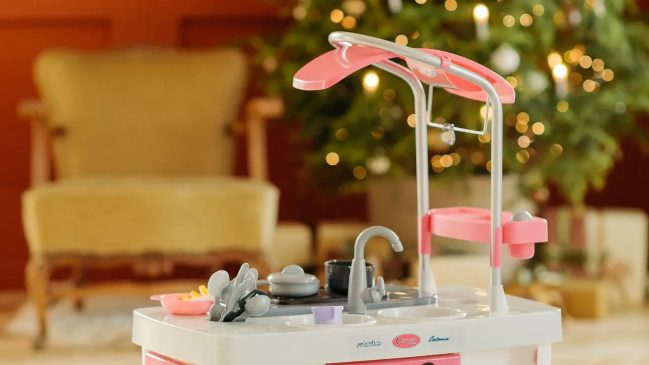 クリスマスツリーの前に置かれたピンク色のおもちゃキッチンセット。子供向けギフトのイメージ。