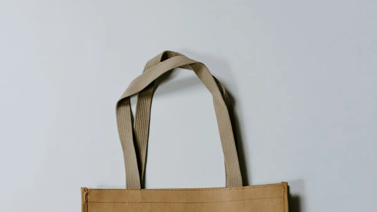 生成り色のクラフト素材のトートバッグの持ち手部分。何も買わずに手ぶらで帰るイメージ。