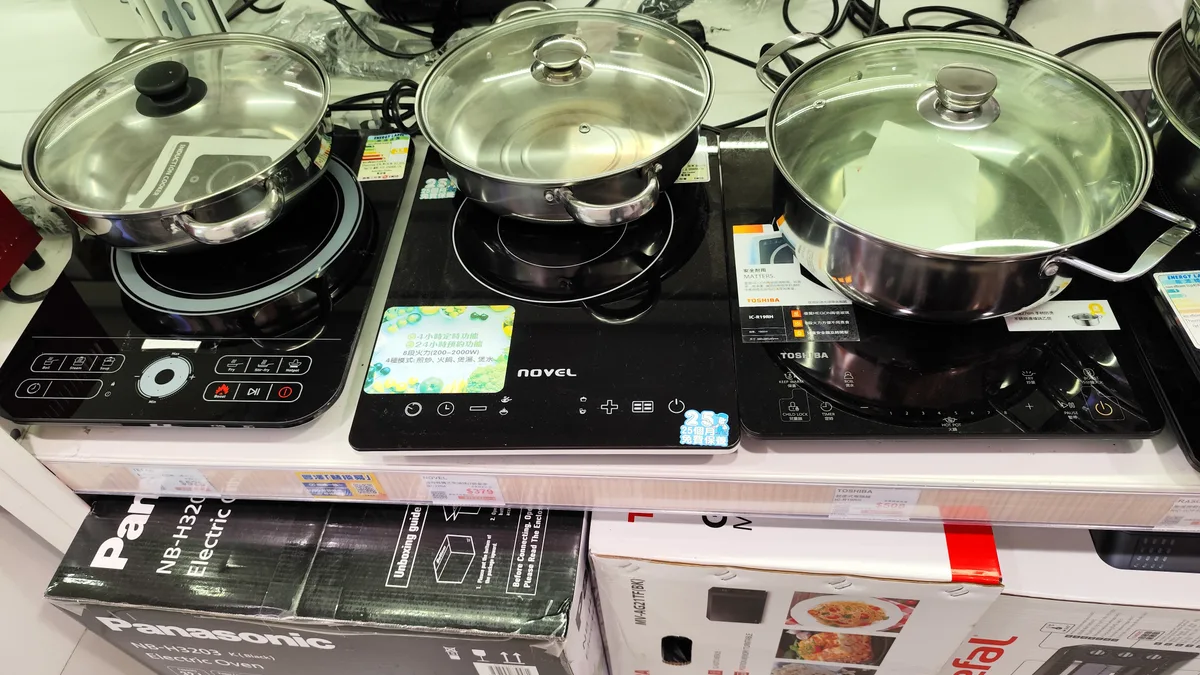 家電売り場の陳列棚。IHクッキングヒーターの実機が並び、それぞれに値札が付いている。