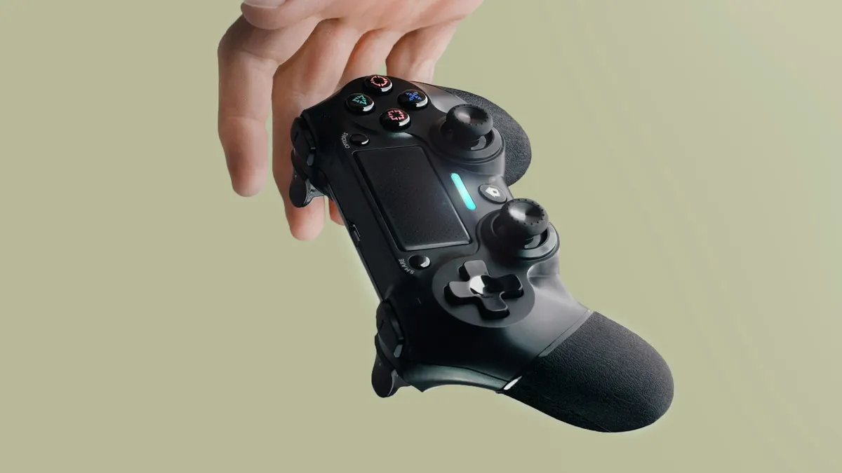 緑がかった背景の前で、手にゲームコントローラーを持っている。