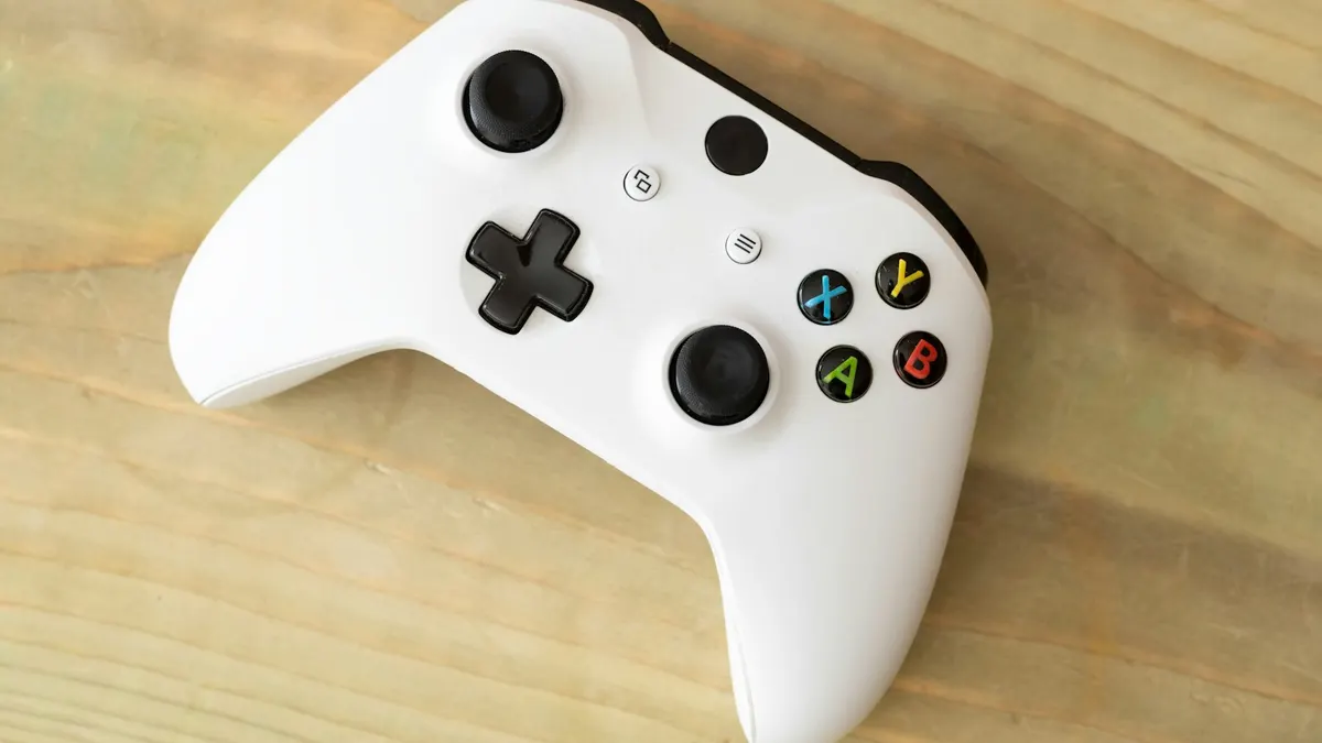 木の机の上に置かれた白いゲームコントローラー。