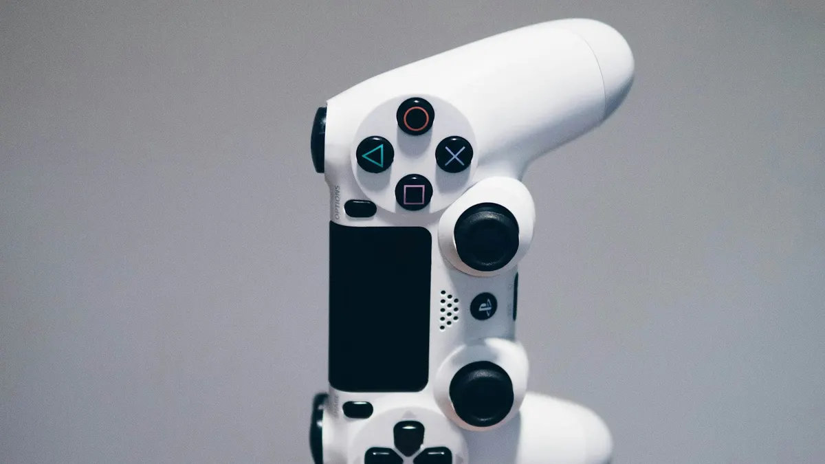灰色の背景の前に立てかけられた白いゲームコントローラー。