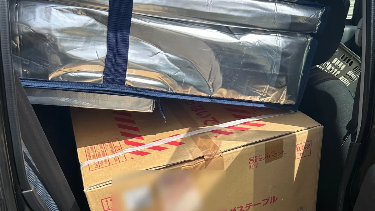 仕入れた商品を車に積み込んだところ。ガスコンロの箱と保冷バッグが後部座席に載っている