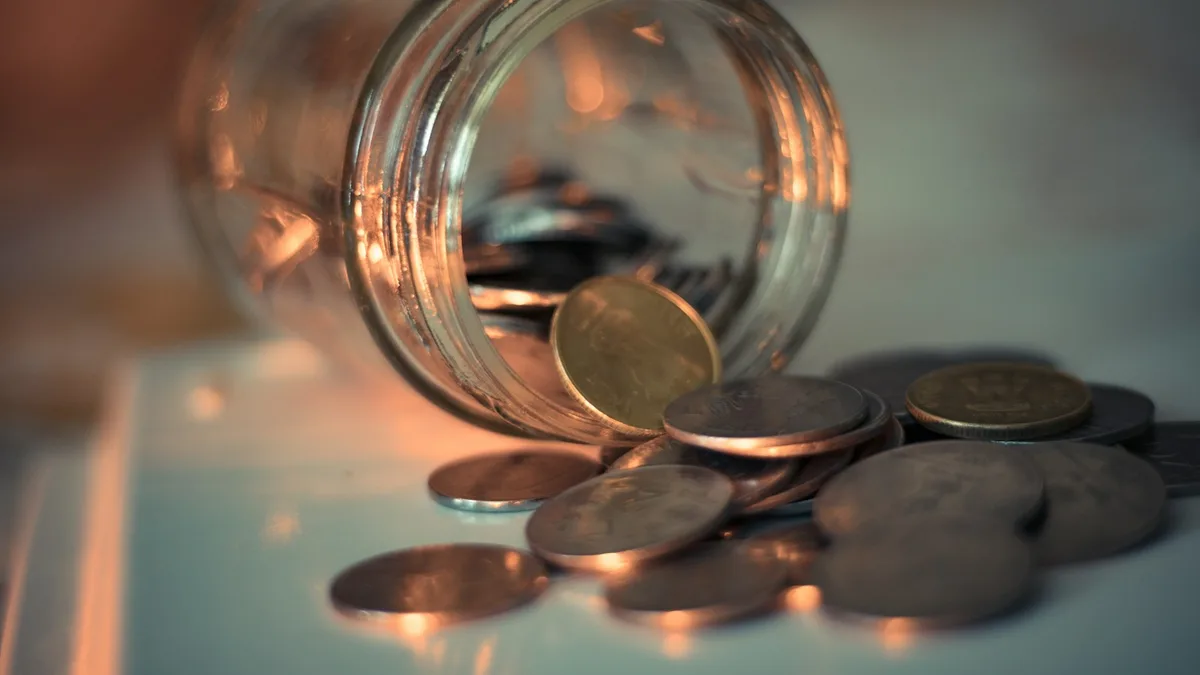 コインがこぼれ出たガラス瓶。待機資金・現金で置いておくお金のイメージ。