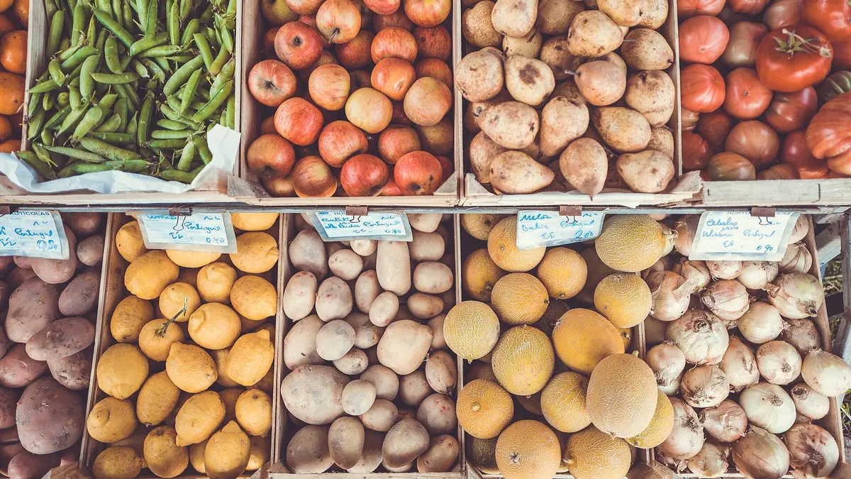 木箱に並べられた市場の野菜と果物。えんどう豆、りんご、じゃがいも、レモン、メロン、玉ねぎ