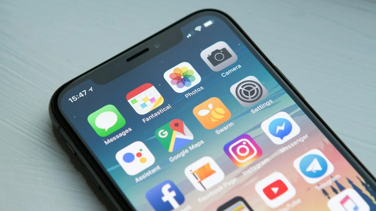 明るい背景に置かれたiPhoneのホーム画面。各種アプリのアイコンが並んでいる。スマホ決済・アプリ活用のイメージ。