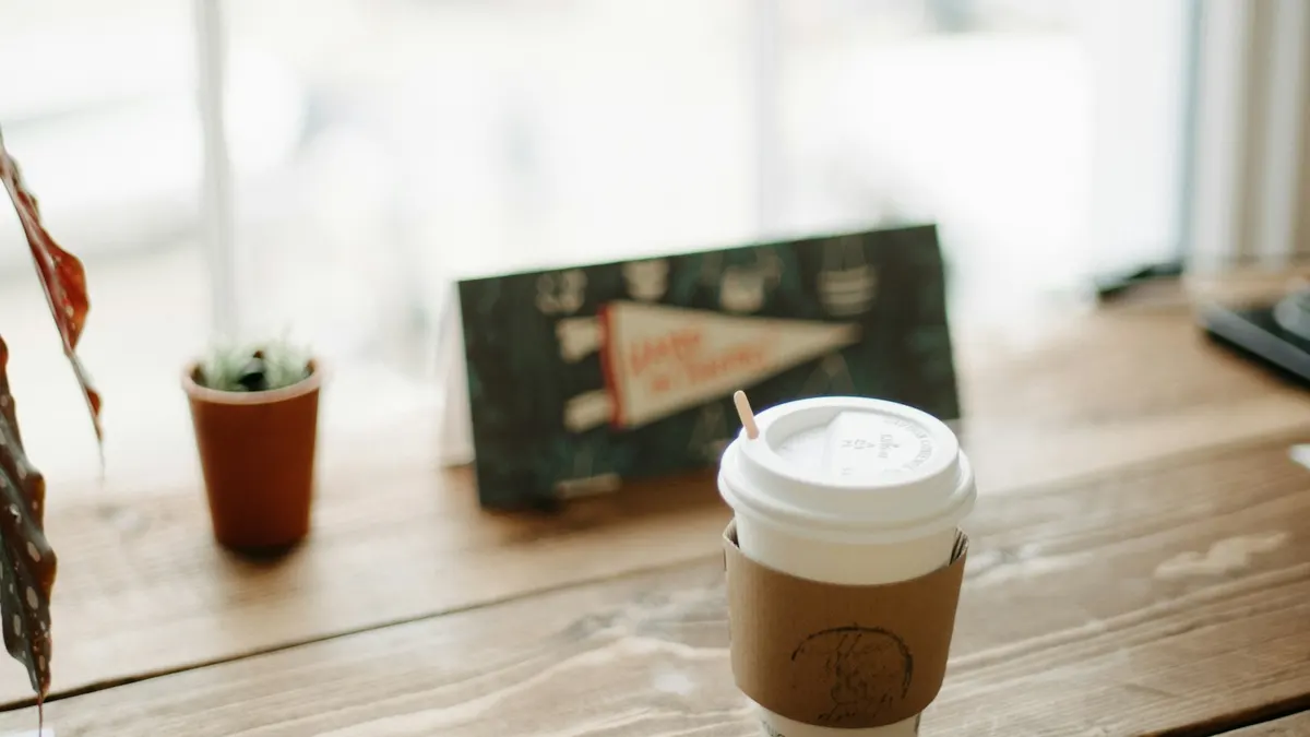 窓辺の片付いた机とコーヒー。日曜の巡回を終えた、落ち着いた振り返りのシーン。