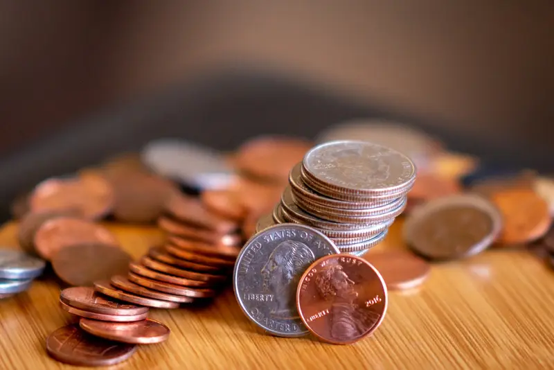 木の机の上に積まれた硬貨。お金の流れを見直すイメージ。