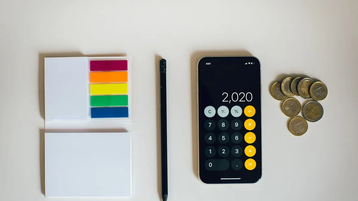 スマートフォンと電卓を並べて、買い物の金額を計算する手元。