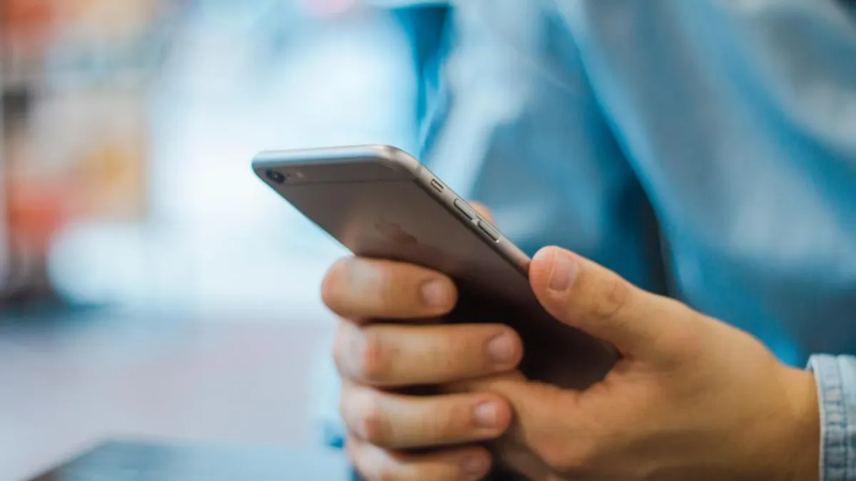 片手でスマートフォンを持ち、画面を操作している手元のクローズアップ