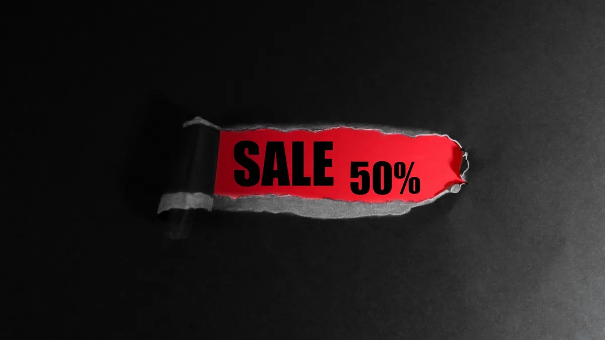 黒い背景に、破れた紙から現れた赤いタグ。「SALE 50%」の文字が白抜きで印刷されている。