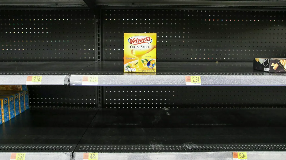 スーパーの陳列棚がほとんど空になっている。棚板に値札のラベルだけが残り、商品が1点だけ置かれている。