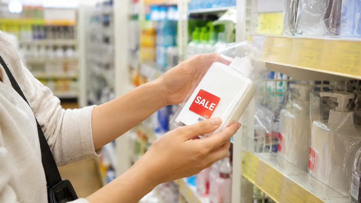 ドラッグストアの棚で割引シールの貼られた商品を手に取っている店頭せどりのシーン