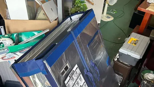 リサイクル店の店内。大型の保冷バッグの周りに工具ケースや扇風機、段ボール箱が雑多に積み重なっている