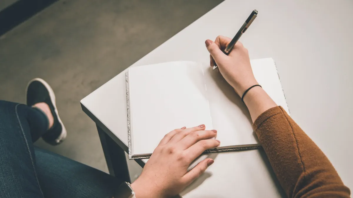 ノートに実売の記録を書き込んでいるイメージ。