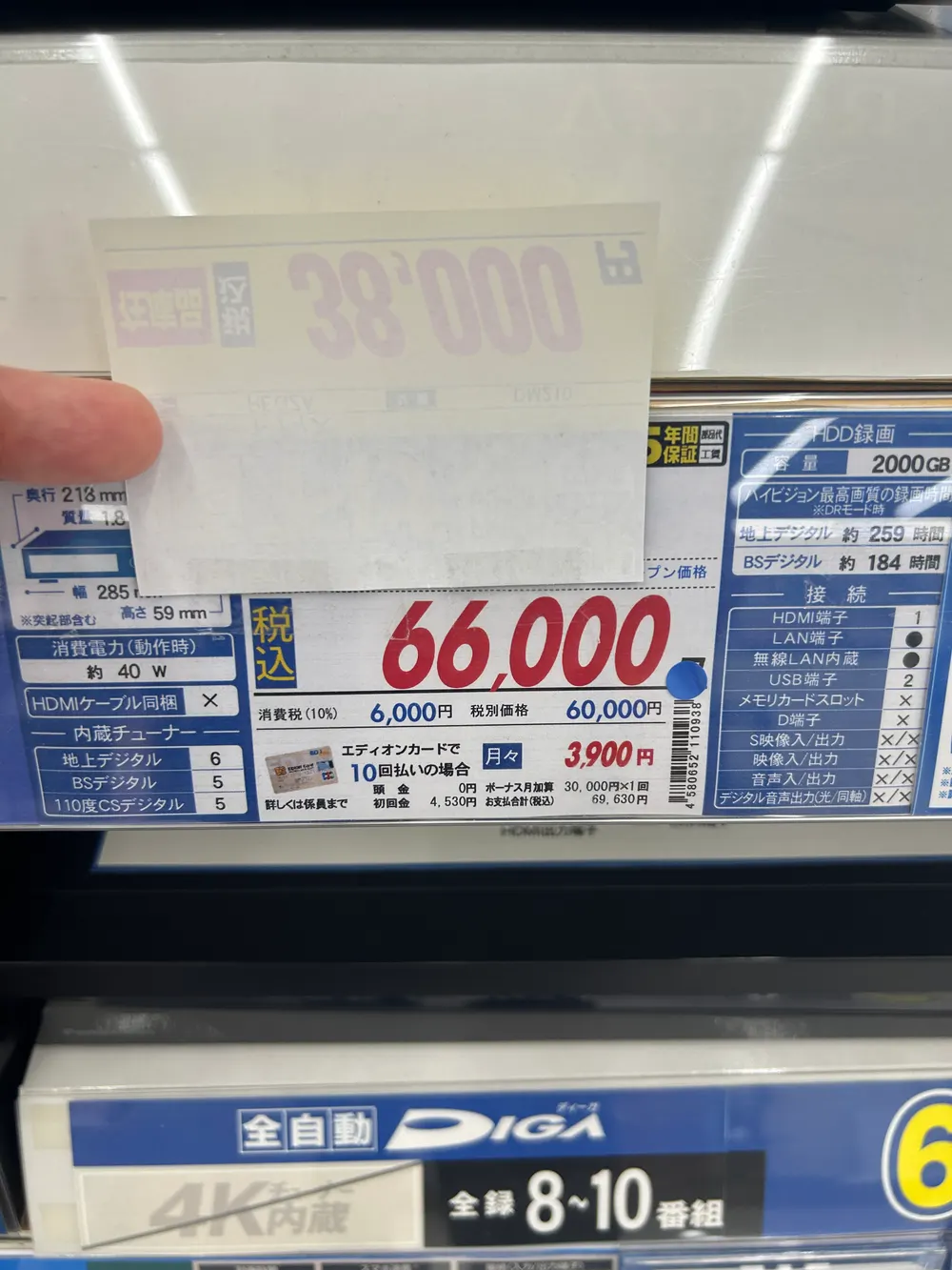 アウトレット札を指で持ち上げて、下にある元の値札を見せている写真。「税込 66,000円 消費税(10%) 6,000円 税別価格 60,000円」「エディオンカードで10回払いの場合 月々3,900円」と書かれている。