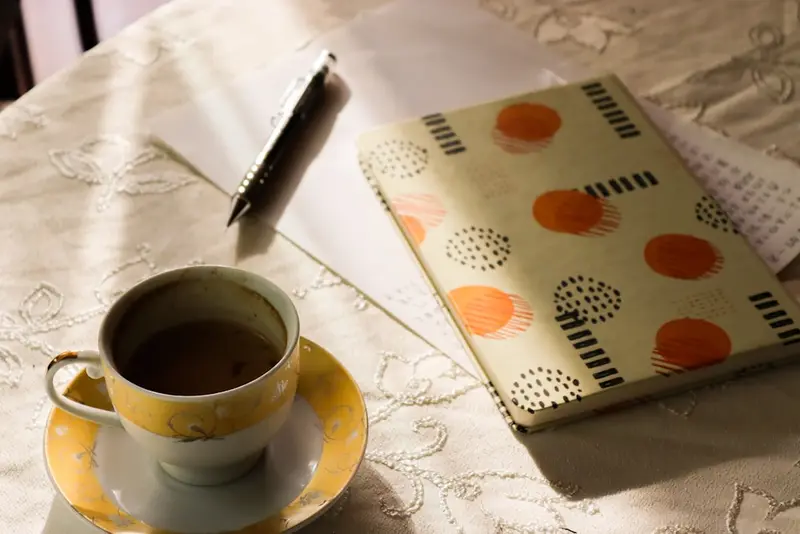 コーヒーカップと、落ち着いて作業する暖色の机まわり。