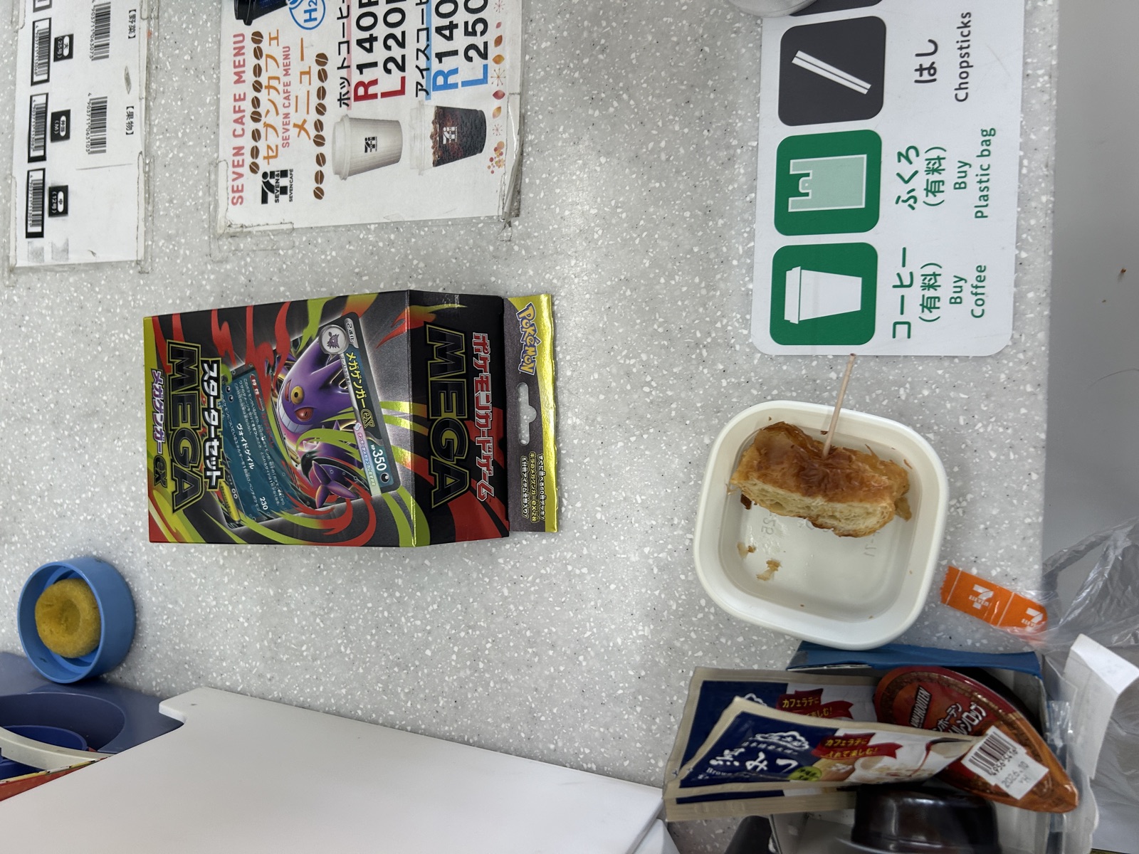 店内のカフェカウンターでコーヒーを飲みながら、戦利品のMEGAスターターセットex 2個を眺めて一服している様子