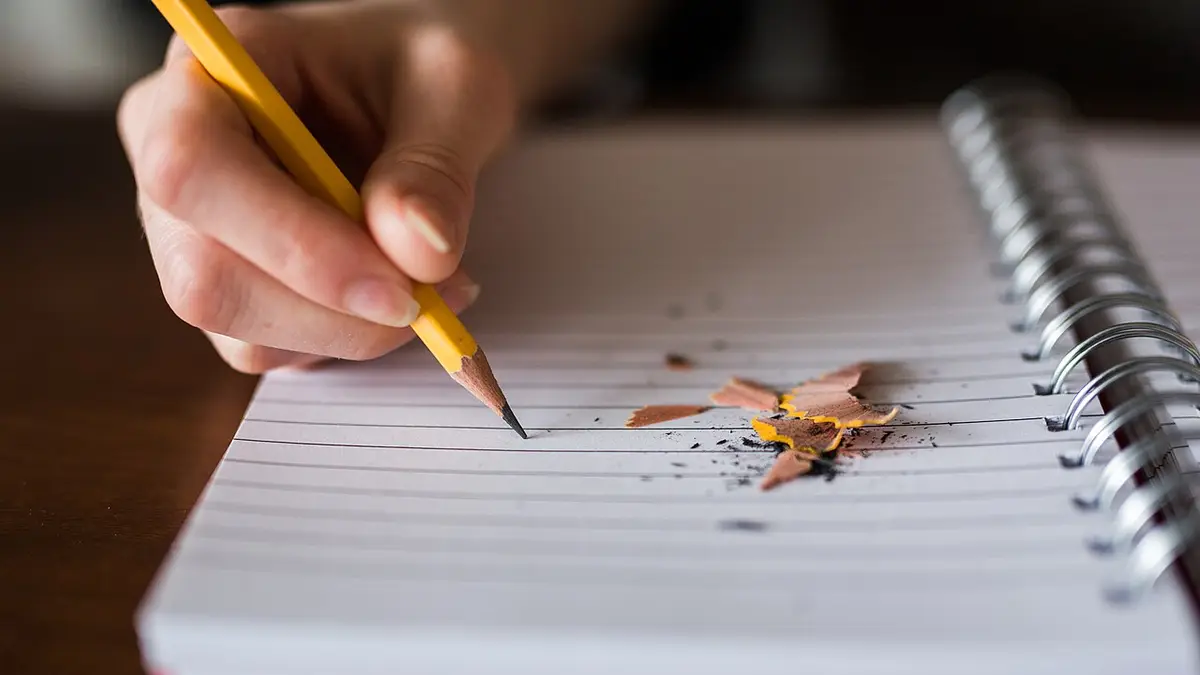 リングノートに鉛筆で書き込む手元。まず支出を書き出して見直し、それから投資に回す順番