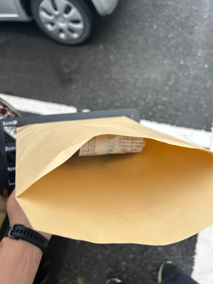 クラフト封筒に、緩衝材で包んだPS5ソフトを入れているところ。駐車場の車内で梱包している。