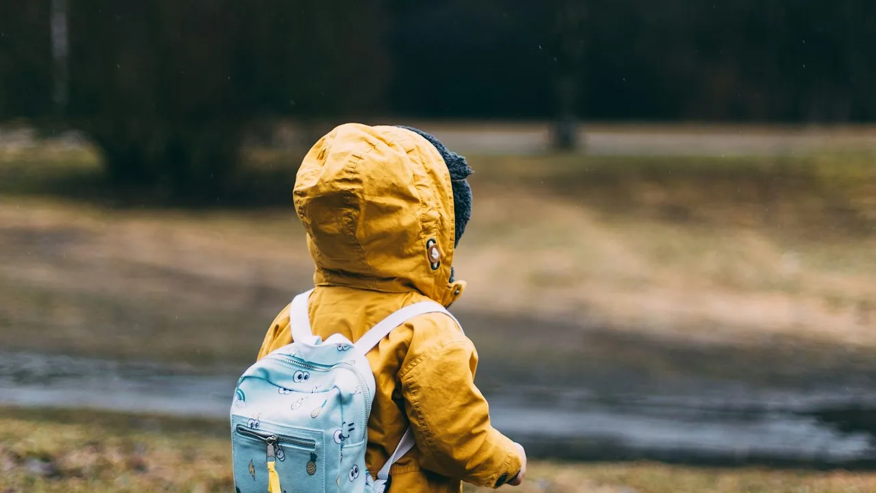 黄色いレインコートを着た子供の後ろ姿。子どもたちの未来のために動き出したイメージ