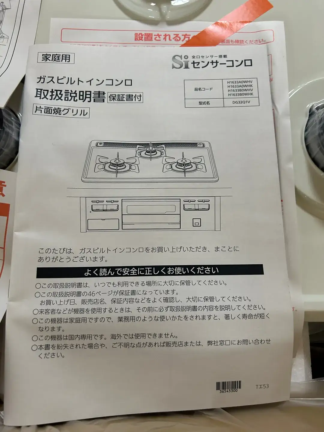 取扱説明書の表紙のアップ。「家庭用 ガスビルトインコンロ 取扱説明書 保証書付 片面焼グリル」の見出しの右に「Si 全口センサー搭載 センサーコンロ」のロゴ。その右の表に「品名コード H1633A0WHV / H1633A0WHK / H1633B0WHV / H1633B0WHK」「型式名 DG32Q1V」と記載されている。下部にはコンロ本体と操作パネルの線画が印刷されている。