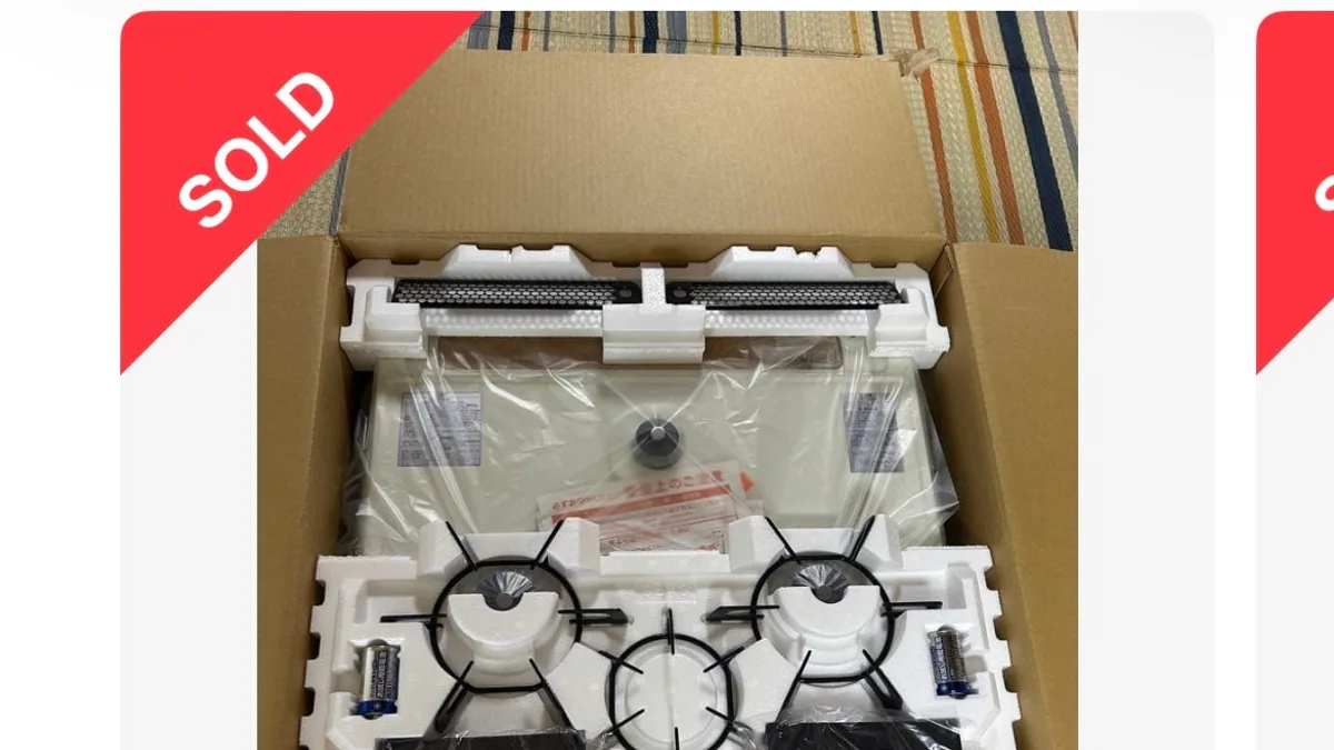 メルカリの商品ページ。商品写真の左上に赤い「SOLD」の帯がかかっている。写真は段ボール箱を開けた状態で、発泡スチロールの緩衝材に五徳2組・中央のリング状ごとく・グリル部品・乾電池が収まり、奥にビニールに包まれた白い天板が見えている。